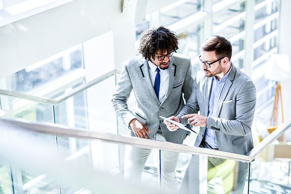 Unterwegs im Gespräch, bleiben zwei Männer dank Mobile Optimization Pro stets vernetzt.