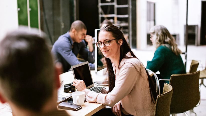 Bild zeigt eine Gruppe von Menschen in einem Großraumbüro während der Arbeit