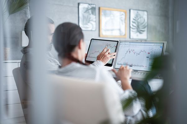 Kolleg:innen analysieren Daten an Tablet und Laptop
