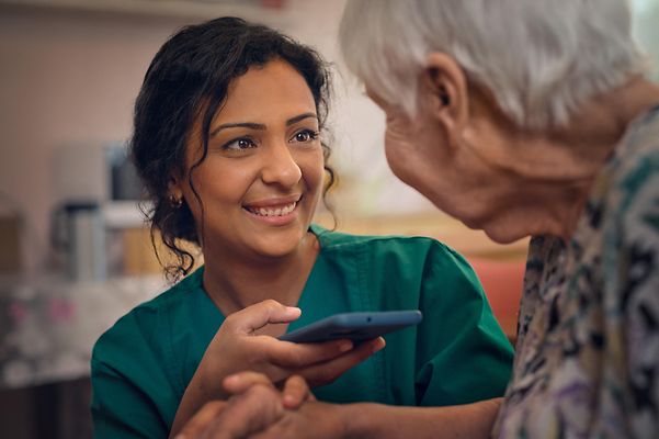 Pflegerin nutzt eine Übersetzungs-App auf ihrem Smartphone
