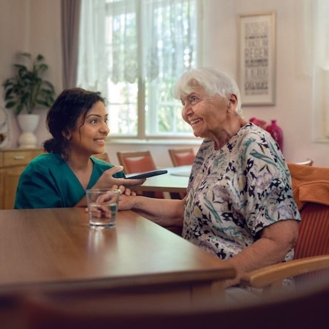 Pflegerin übersetzt simultan über ihr Smartphone für eine ältere Frau