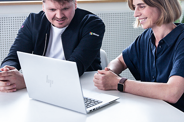 Berater sitzt mit einer Kundin zusammen und berät Sie zu Microsoft Teams Telefonie von der Telekom