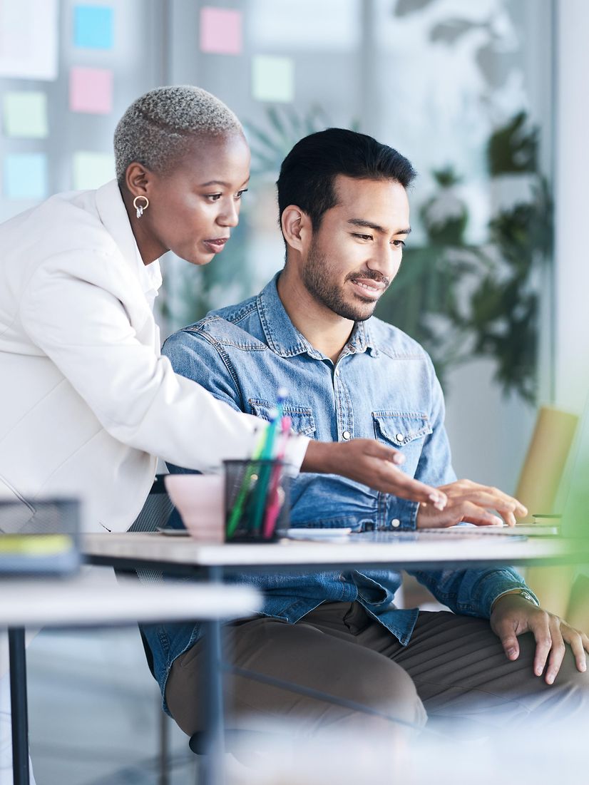 Zwei Personen, eine Frau und ein Mann, sprechen miteinander an einem Schreibtisch