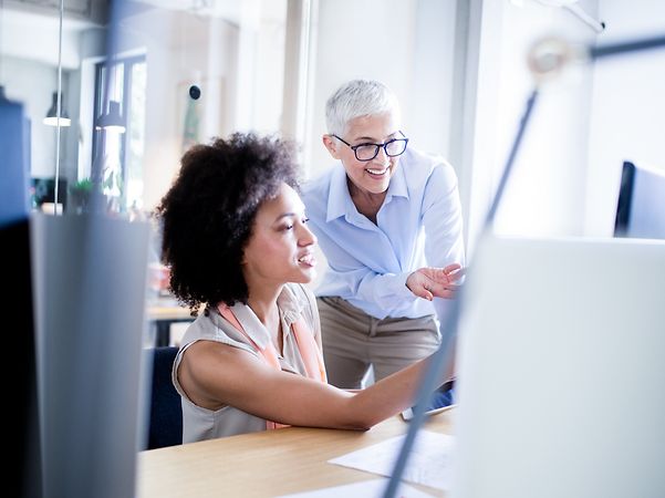 Zwei Frauen besprechen ein Projekt vor einem Computerbildschirm