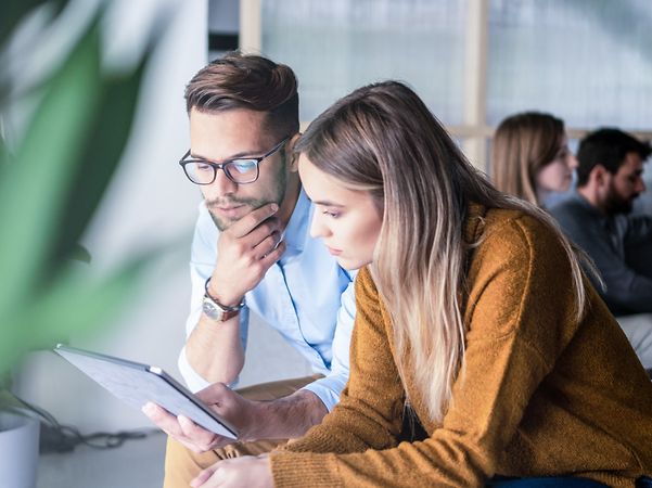Zwei Personen diskutieren ein Projekt an einem Tablet