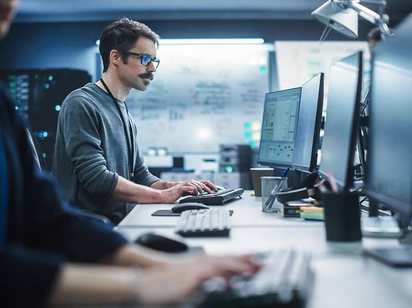 Ein Mann sitzt in einem Cyber-Kontrollzentrum am Computer