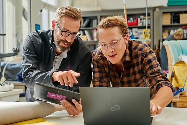 Kunde und Telekom Mitarbeiten schauen gemeinsam auf einen Laptop
