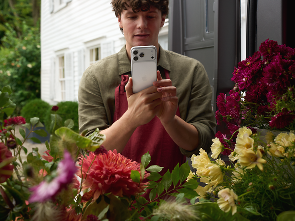 Florist fotografiert mit einem iPhone 17 Pro seine Blumen für die Kunden. 